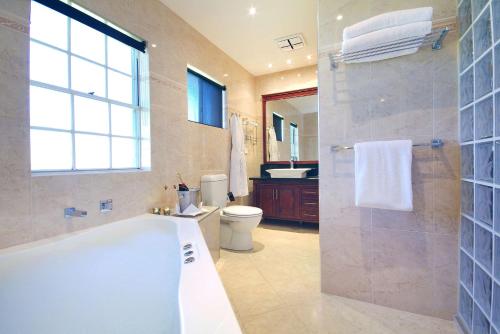 a bathroom with a tub and a toilet and a shower at Rydges Armidale in Armidale
