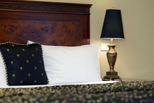 a bed with a black and white pillow and a lamp at Rydges Armidale in Armidale