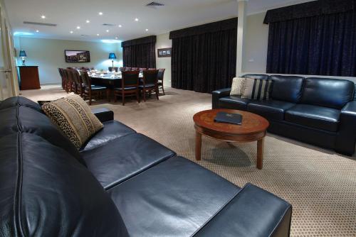 a living room with a black leather couch and a table at Rydges Armidale in Armidale