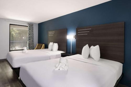 um quarto de hotel com duas camas com almofadas brancas em Suburban Studios em Hinesville