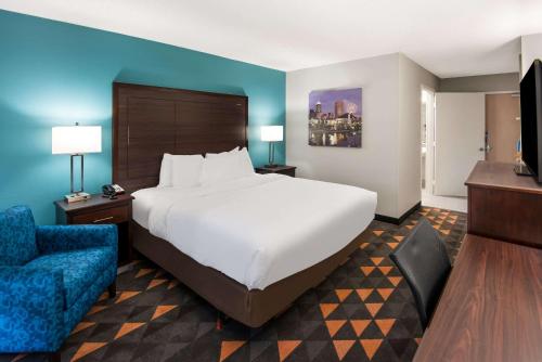 Habitación de hotel con cama grande y pared azul en Clarion Pointe Indianapolis Northeast en Castleton