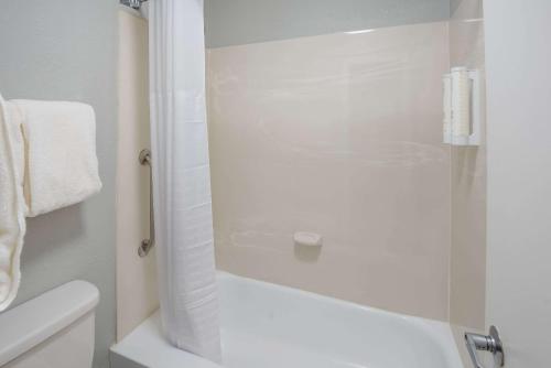 a bathroom with a shower with a white tub and a toilet at Clarion Pointe Indianapolis Northeast in Castleton