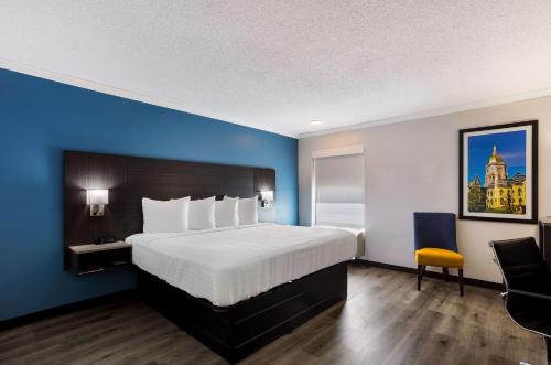 a bedroom with a large bed and a blue wall at Quality Inn South Bend near Notre Dame in South Bend