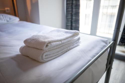 a stack of towels sitting on a bed at Hotel Bristol in Luxembourg