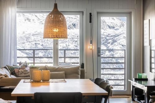 ein Wohnzimmer mit einem Tisch vor zwei Fenstern in der Unterkunft Skarsnuten Panorama 46 in Grøndalen