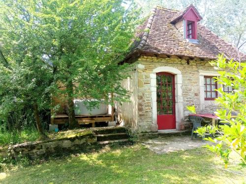 een oud stenen huis met een rode deur bij Maison de poupée et son SPA privatif in Orthez