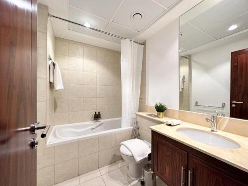 y baño con bañera, aseo y lavamanos. en Durrani Homes - Grand 5BR besides Burj khalifa and Fountain view en Dubái