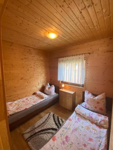 a room with two beds in a wooden cabin at Domek Standard 2 in Darłowo