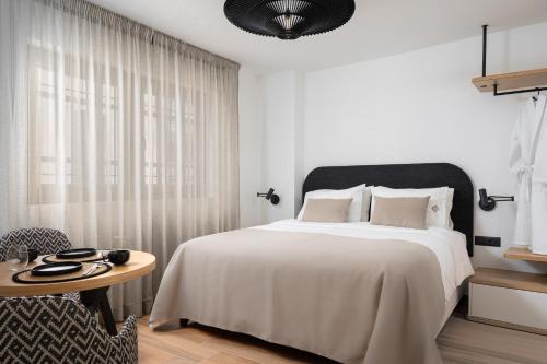 a bedroom with a large white bed and a table at Casa di Gaga Luxury Suites in Rethymno Town