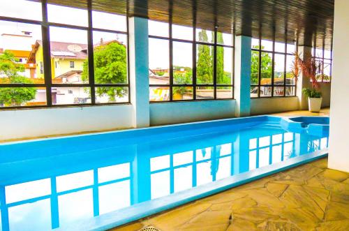 a large swimming pool in a building with windows at Hotel Alpenrose in Treze Tílias
