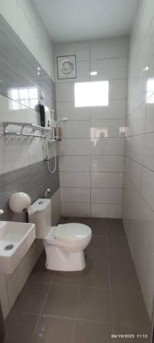 a white bathroom with a toilet and a sink at Spacious Room in Gunung Ledang 