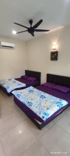 two beds in a room with a ceiling fan at Spacious Room in Gunung Ledang 