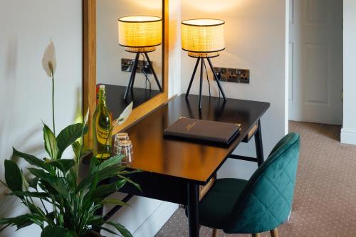 a desk with two lamps and a green chair at The Imperial Dragon Hotel in Saundersfoot