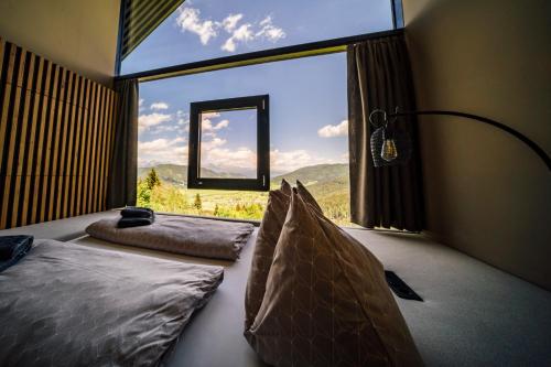 a bedroom with two beds and a large window at Hüttendorf Schlögelberger in Sankt Margarethen im Lungau