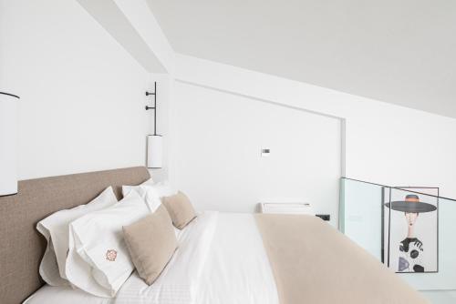a bedroom with a white bed with white pillows at Casa di Gaga Luxury Suites in Rethymno Town