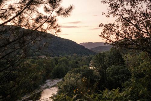 a view of a river with trees and mountains at Slow Village Anduze - Cévennes in Corbés