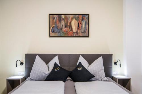 uma cama com almofadas pretas e brancas e um quadro em Laube35 Central City Apartments em Vipiteno