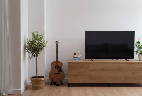 sala de estar con TV en un armario con guitarra en Spacious and fully equipped apartment near Zadar, en Smoković