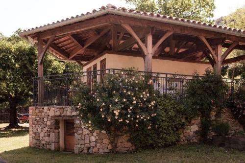 a wooden pergola with a bush with white flowers at Slow Village Anduze - Cévennes in Corbés