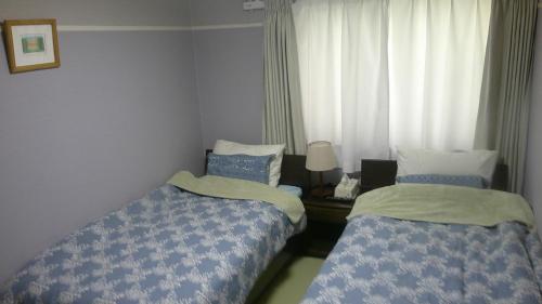 1 dormitorio con 2 camas y ventana en 旅の宿ていね, en Sapporo