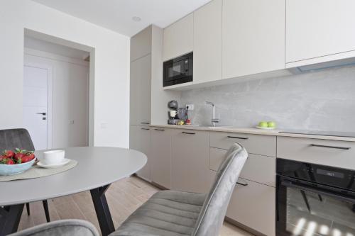 ウテナにあるAušros apartamentaiの白いキャビネット、テーブルと椅子付きのキッチンが備わります。