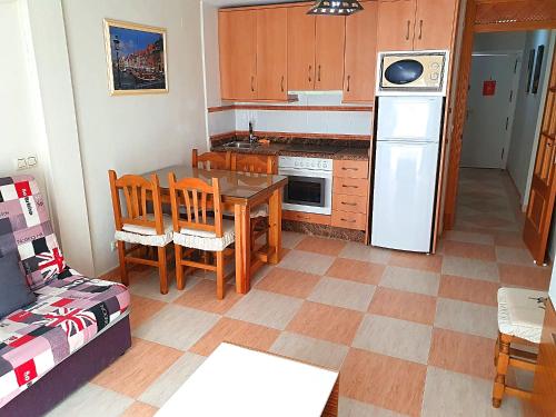 eine Küche mit einem Tisch und einem weißen Kühlschrank in der Unterkunft One bedroom in Benidorm Playmon Park in Benidorm