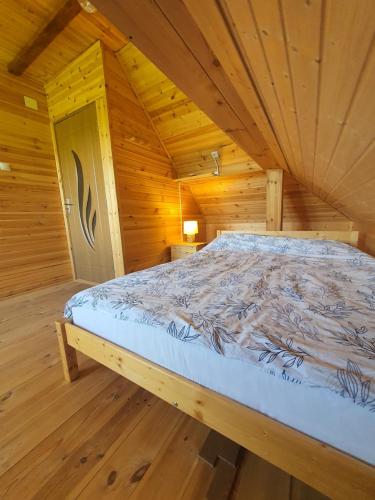 a bed in a wooden cabin with a wooden floor at Almost Heaven - cabană cu vedere în Apuseni in Cîmpeni