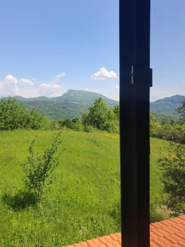 a view of a green field from a window at Almost Heaven - cabană cu vedere în Apuseni in Cîmpeni