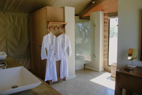 a bathroom with white shirts hanging on a rack at Die Boskamp Self-Catering Bush Retreat in Marble Hall