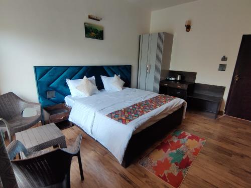 a bedroom with a large bed with a blue headboard at Aranya Mukteshwar in Mukteswar