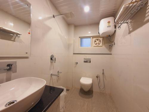 ein weißes Badezimmer mit Waschbecken und Toilette in der Unterkunft Maywood Hotel in Shimla