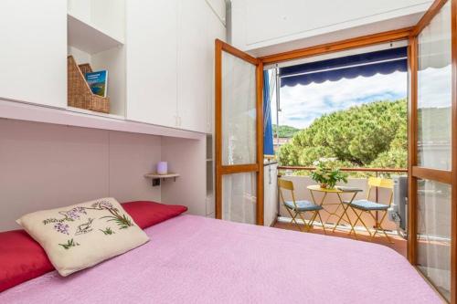 ein Schlafzimmer mit einem rosa Bett und einem Balkon in der Unterkunft Ambra Marina, la casa tra i pini a Rapallo! in Rapallo