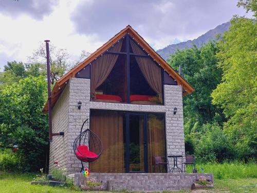 een klein huis met een rode stoel ervoor bij Iano in Oni