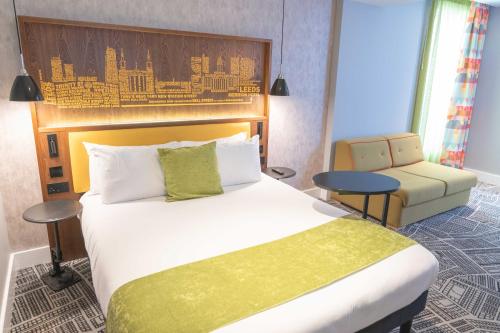 a hotel room with a large bed and a chair at ibis Styles Leeds City Centre Arena in Leeds