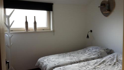 a bedroom with a bed and a window at Stal Zwartschaap in Stuifzand