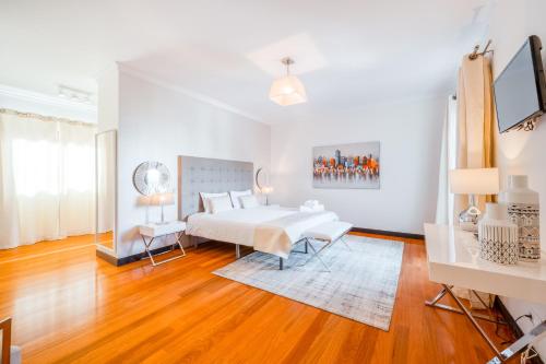 a white bedroom with a bed and a wooden floor at Villa Vacuna in Funchal