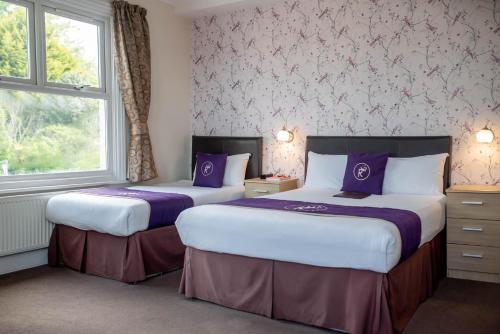 two beds in a hotel room with a window at Revado Hotel in Norwich