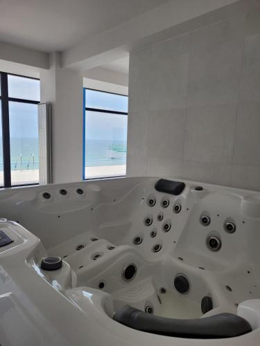 a white bath tub in a room with two windows at DAMAR Infinity Beach and Pool Mamaia- private parking in Mamaia Sat/Năvodari