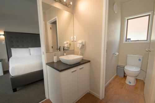 uma casa de banho com um lavatório, um WC e uma cama em Middlemore Motel em Auckland