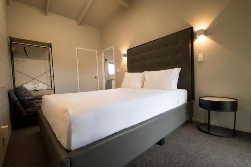 a bedroom with a large white bed and a chair at Middlemore Motel in Auckland