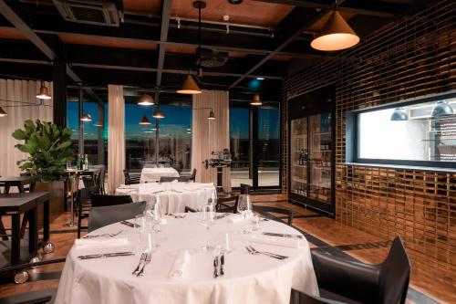 a restaurant with white tables and chairs and a projection screen at Winery & Design hotel ROXANICH in Motovun