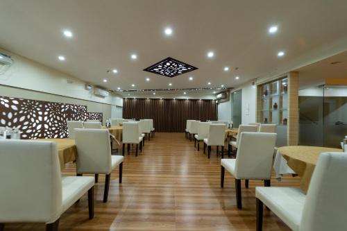 a dining room with tables and white chairs at Tetrad Hotels - International Airport Road Hebbal in Bengaluru
