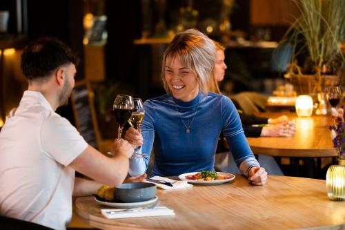 a woman sitting at a table with a glass of wine at Hotel Marktstad in Schagen