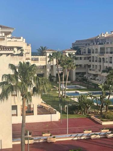 uma vista para um edifício com palmeiras e edifícios em Vereda Golf - Apartamento em Roquetas de Mar