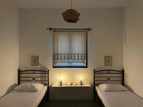 Duas camas num quarto com uma janela e um lavatório em Anevalousa Beach House em Moutsoúna