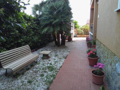 eine Parkbank neben einem steinernen Gehweg mit Pflanzen in der Unterkunft Appartamento Loretta in Marciana Marina