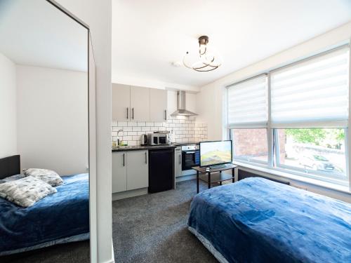 a bedroom with a bed and a kitchen with a window at Mansfield Town Centre Flats in Mansfield