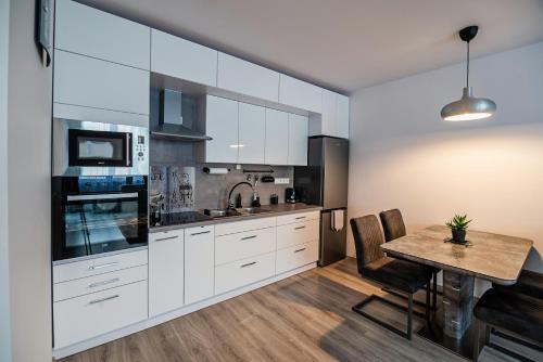 塞克什白堡的住宿－City Apartman Székesfehérvár，厨房配有白色橱柜和木桌