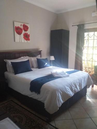 a bedroom with a large white bed with blue pillows at Africa Dawn Guesthouse in Musina