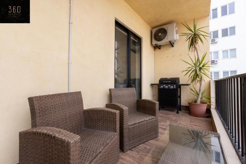 a balcony with two chairs and a television on a building at Beautiful, spacious 3BR home with private Balcony with 360 Estates in St. Julianʼs